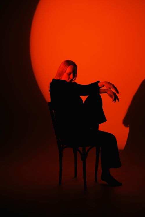 Free Artistic silhouette of a woman sitting on a chair against a vivid red backdrop. Stock Photo