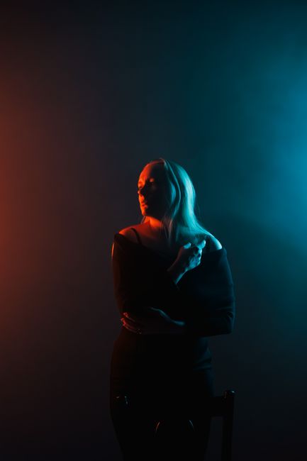 Dramatic portrait of a woman in colored light, blending warm and cool tones for an artistic effect.