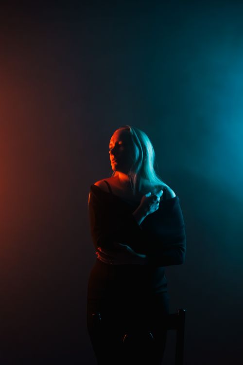 Free Dramatic portrait of a woman in colored light, blending warm and cool tones for an artistic effect. Stock Photo