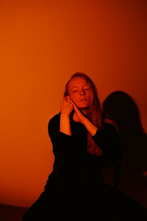 Free Artistic portrait of a person in warm orange lighting with a contemplative expression. Stock Photo