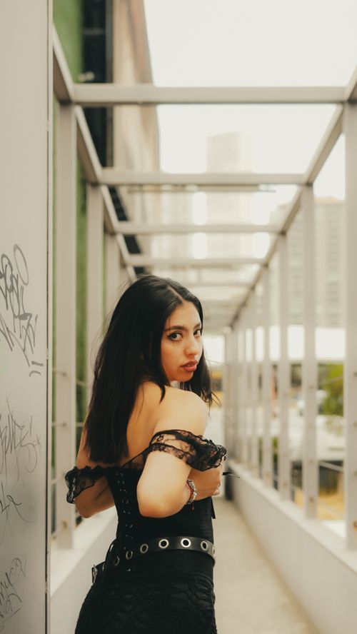 Free Young woman in fashionable outfit poses in urban outdoor location, exuding confidence. Stock Photo