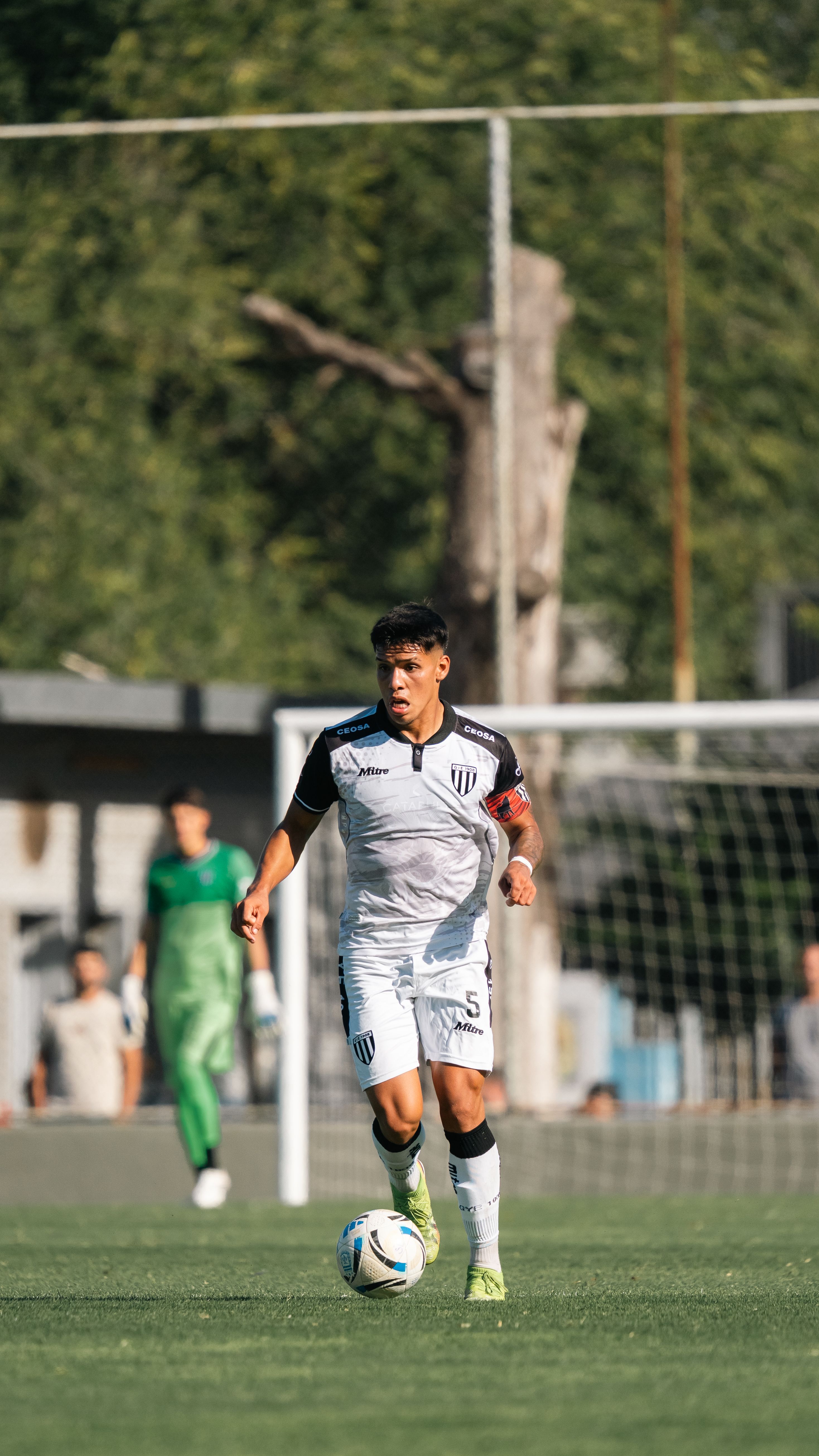 A focused soccer player dribbling on an outdoor field during a match, exhibiting determination and skill.