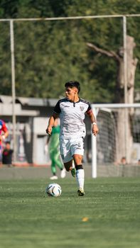 Male soccer player controlling the ball on a sunny outdoor field during a match.