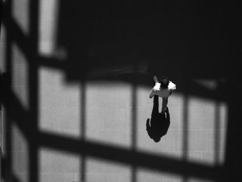 Free A dynamic aerial shot of a man walking with dramatic shadows indoors. Stock Photo