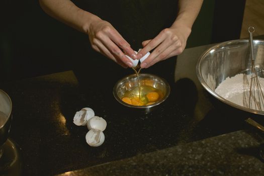Hands cracking eggs into a bowl, with flour ready for baking. Perfect for culinary scenes.