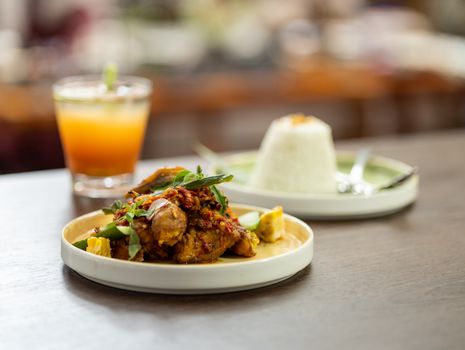 Savor the flavors of a traditional Indonesian dish served with fresh juice and rice.