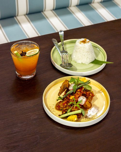 Free Indonesian spiced chicken with rice and a refreshing fruit juice on a wooden table. Stock Photo