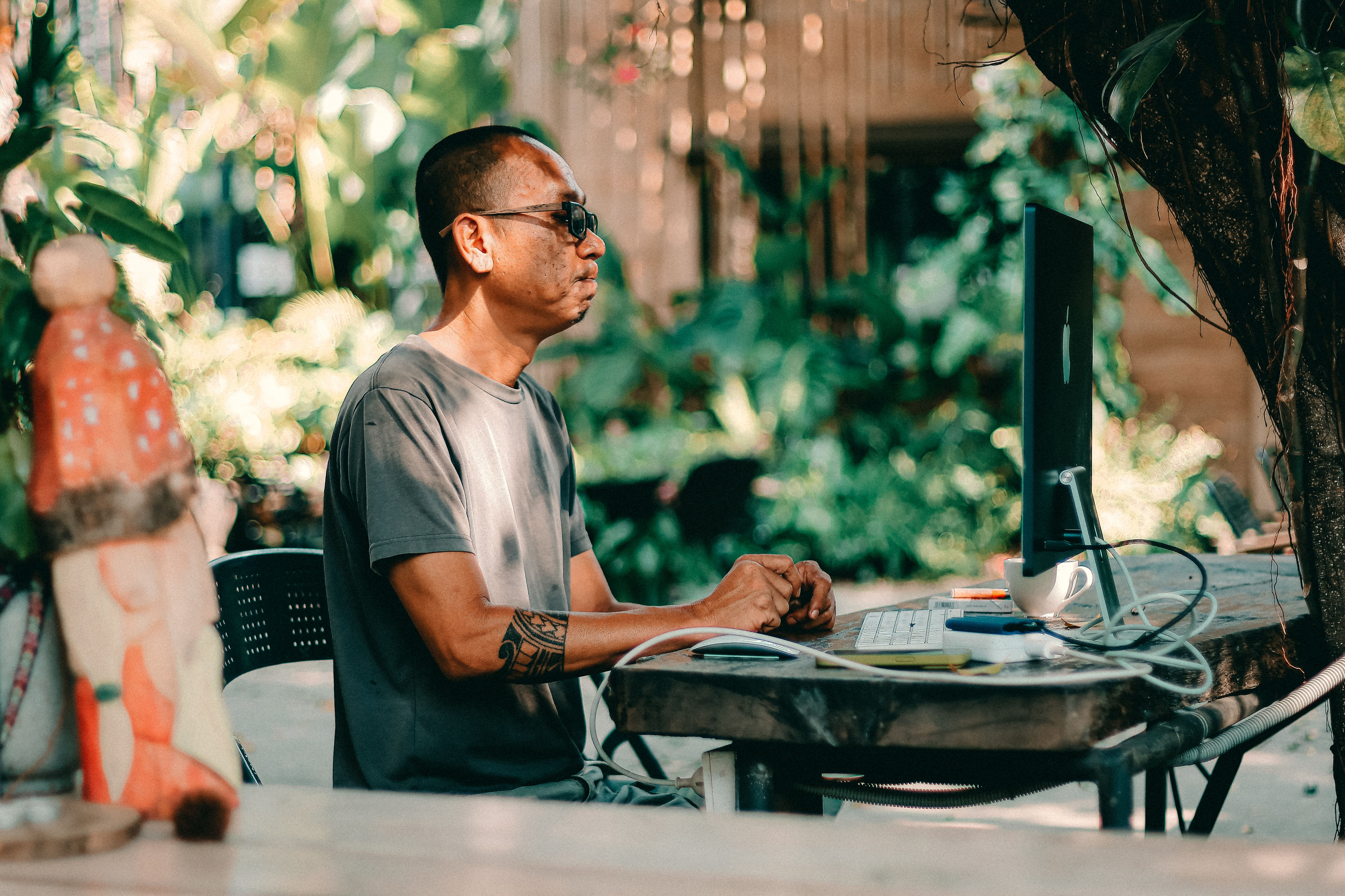 Man Working Outdoors on Computer in Garden Setting