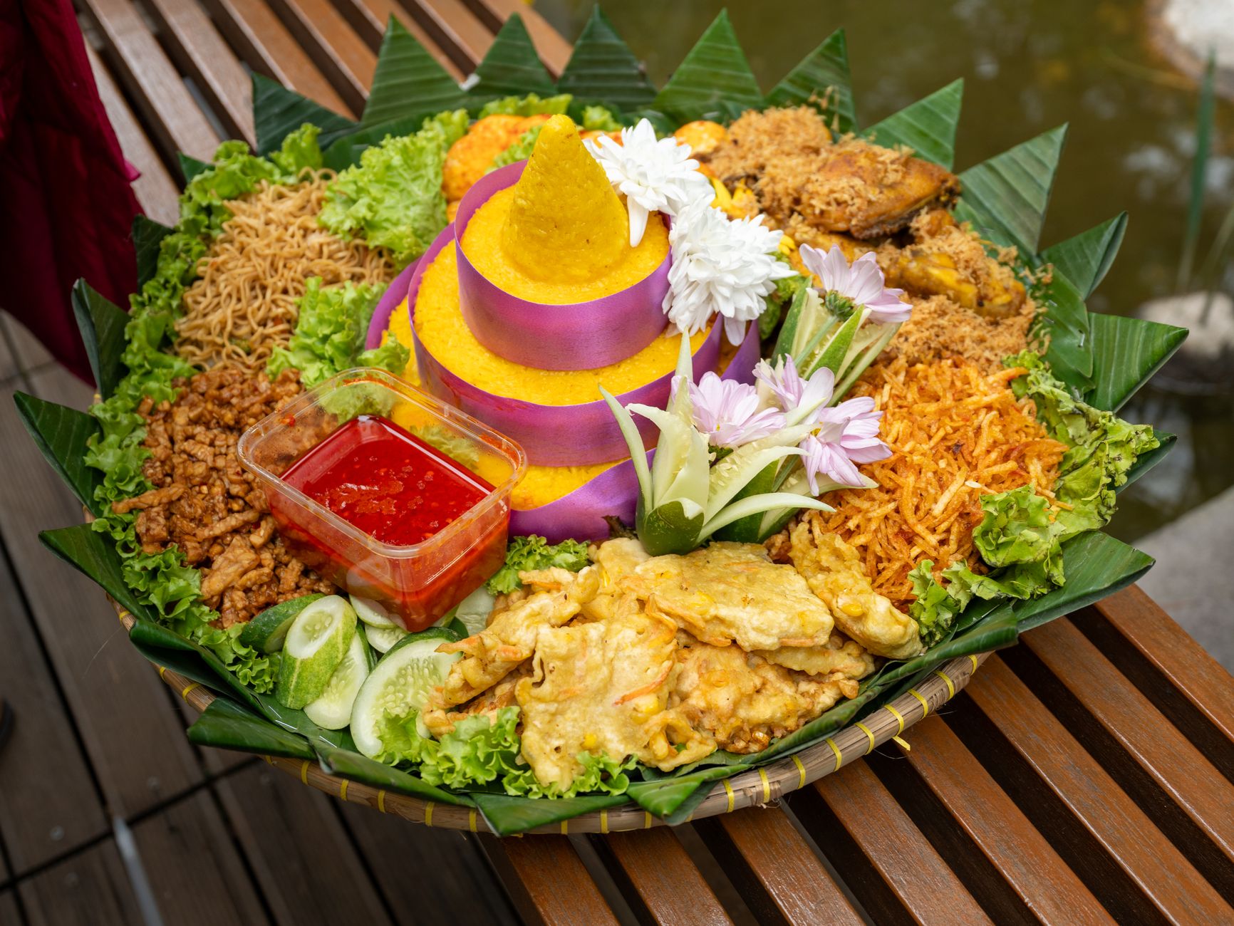 Sajian nasi Tumpeng Indonesia yang semarak, dikelilingi berbagai lauk pauk dan hiasan tradisional.