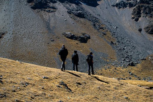 Three hikers explore a rocky landscape in Cusco, Peru, under clear blue skies.