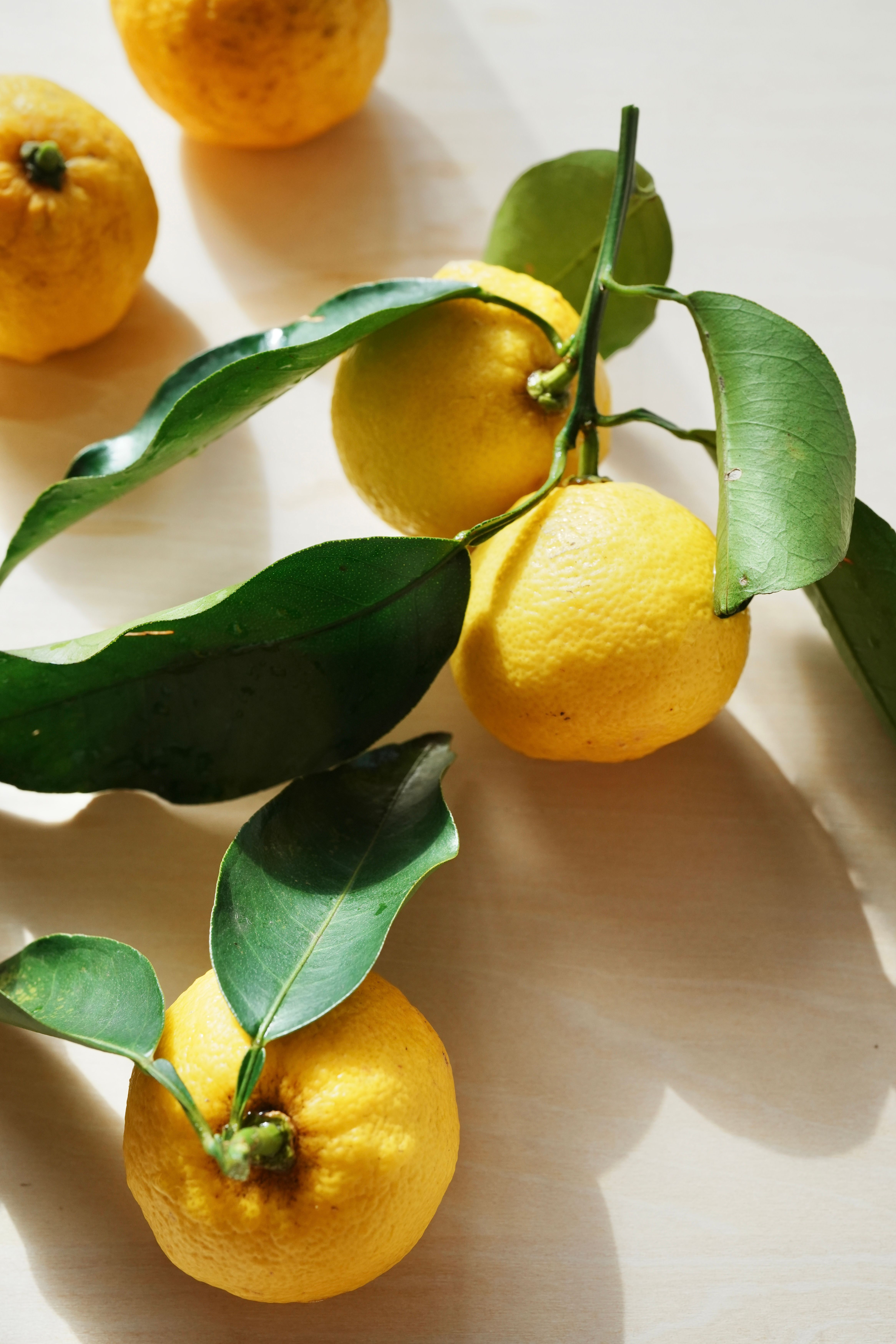 Bright yellow citrus fruits with green leaves in natural light on a table.