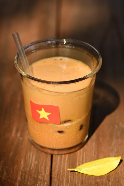 Free Glass of Vietnamese iced coffee with flag sticker on a wooden table. Stock Photo