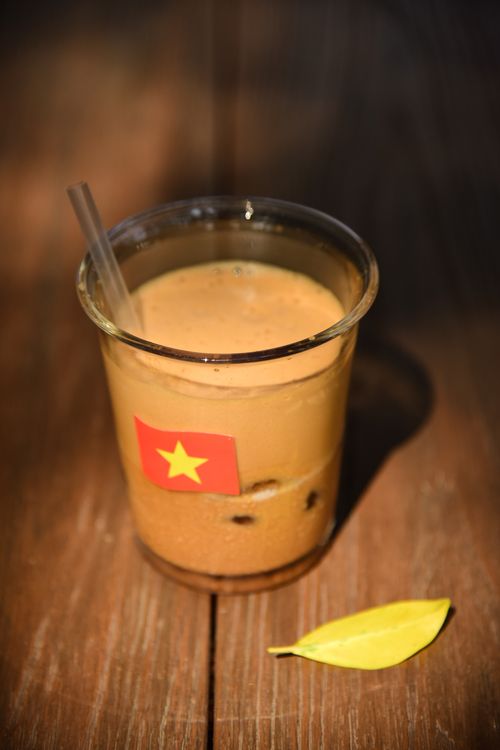 Free Glass of Vietnamese iced coffee on wooden table with flag sticker. Stock Photo
