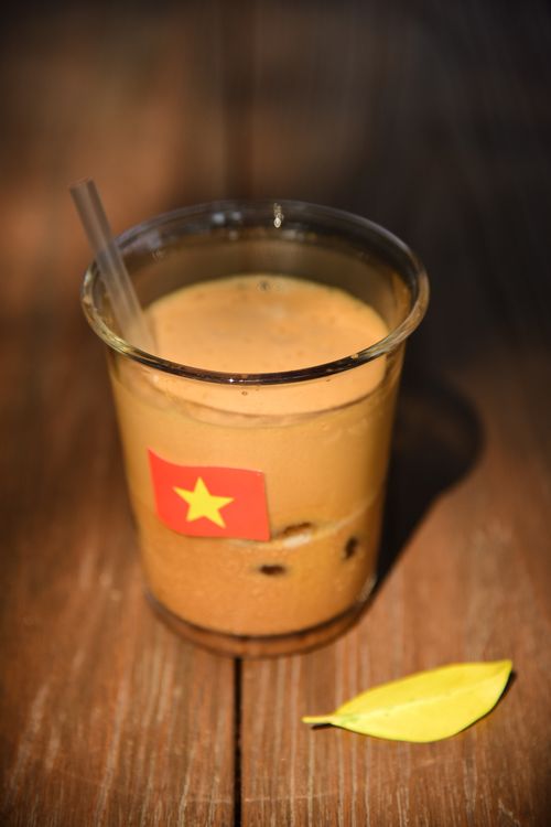 Free Glass of Vietnamese iced coffee with a flag sticker on a wooden table. Stock Photo