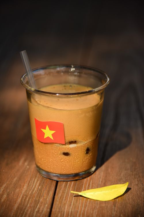 Free Glass of Vietnamese iced coffee with a straw, marked by national flag, on a sunny day. Stock Photo