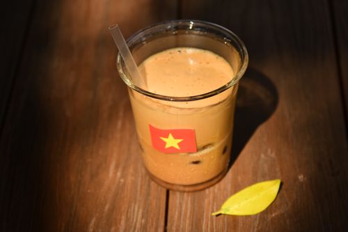 Free Glass of Vietnamese iced coffee with flag sticker on a wooden table. Stock Photo