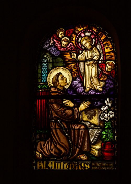 Free Colorful stained glass featuring a saint in prayer with angels. Stock Photo