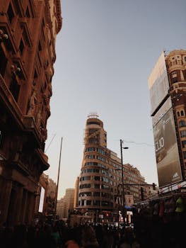 A bustling scene of Madrid's Calle Gran Vía with the prominent Edificio Capitol at dusk, capturing the city's vibrant energy.