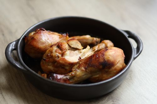 Free Appetizing roasted chicken drumsticks served in a black pan. Stock Photo