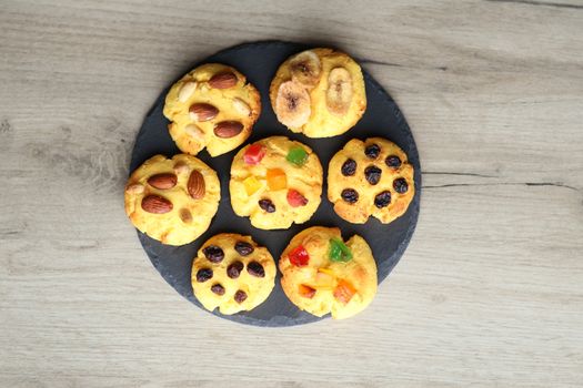Top view of six assorted cookies with fruits and nuts on a slate platter.