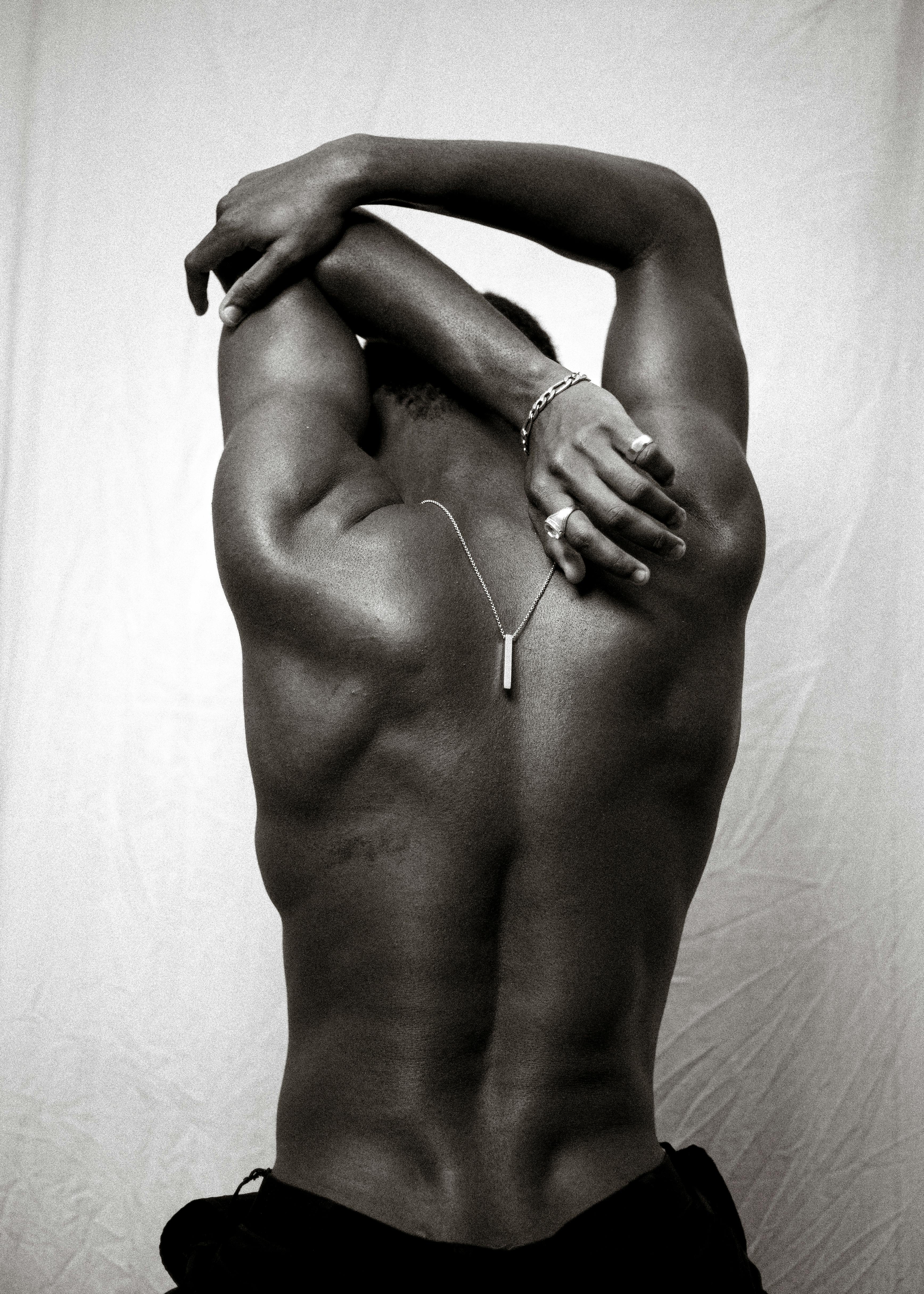 Black and white photo of a man's back showcasing muscle definition and artistic composition.