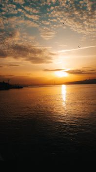 A vibrant sunset over a calm ocean with golden reflections on the water surface.