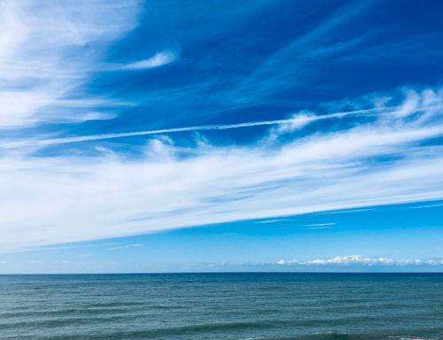 Free Peaceful ocean landscape with clear blue sky and delicate clouds, evoking a sense of calm and tranquility. Stock Photo