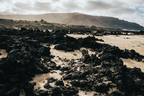 Free Rugged volcanic terrain at Lanzarote, showcasing dramatic natural scenery under cloudy skies. Stock Photo