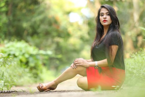 Free Stylish fashion portrait of an Indian woman sitting outdoors with greenery background. Stock Photo