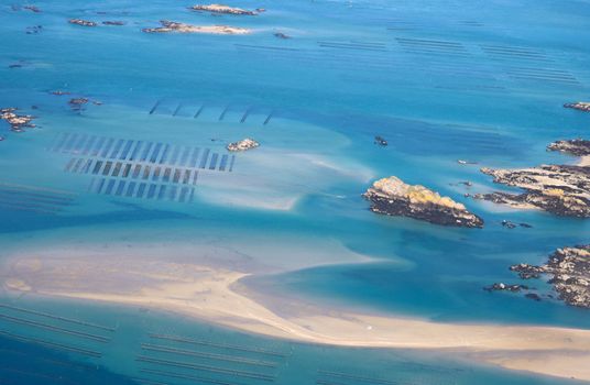 Stunning aerial capture of oyster farms and rocky coastline in Normandie, France.