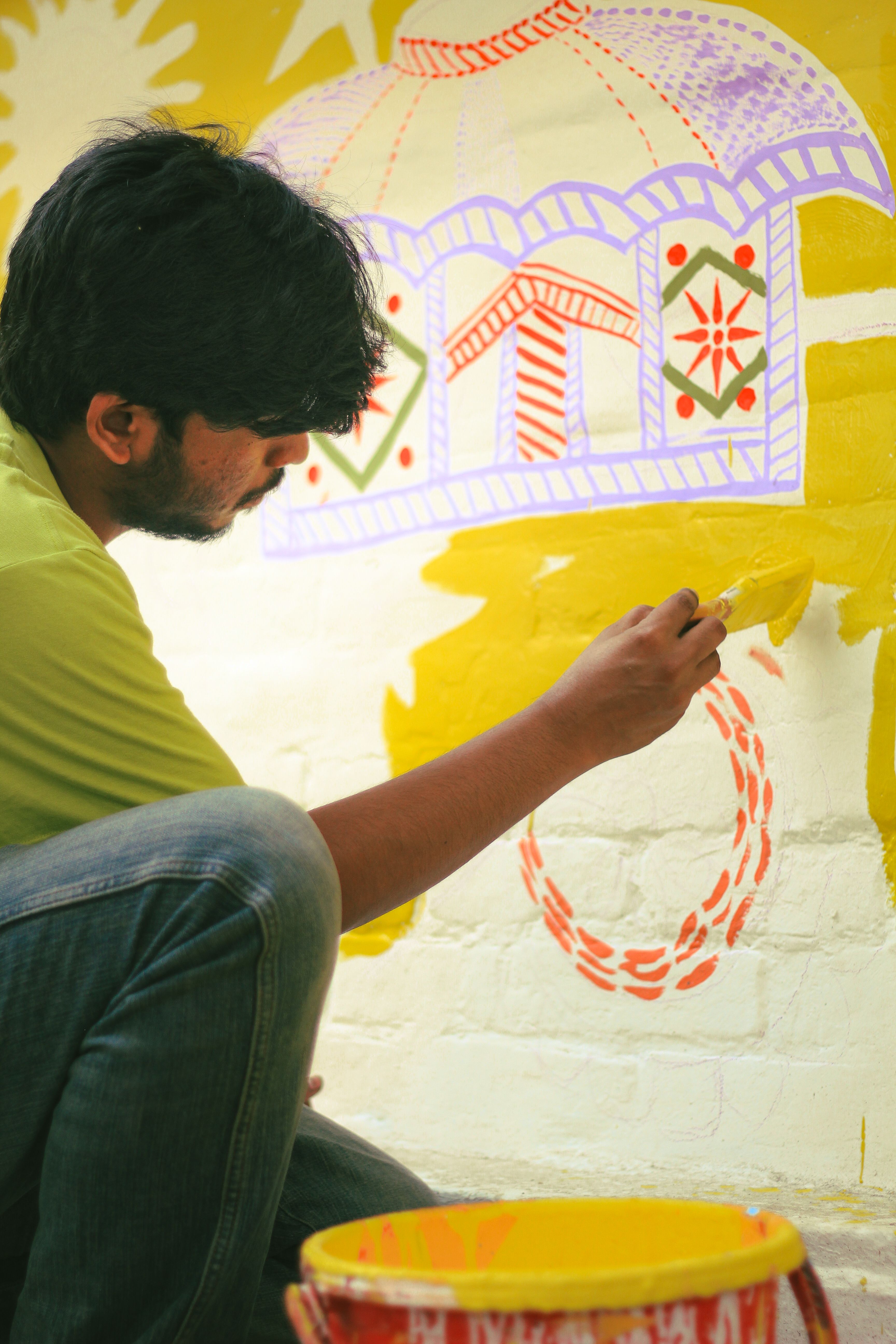 A man paints a colorful mural in Dhaka, capturing artistic creativity and cultural expression.