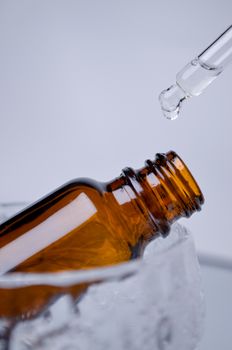 Amber glass dropper bottle with liquid being dispensed, highlighting skincare or essential oil use.