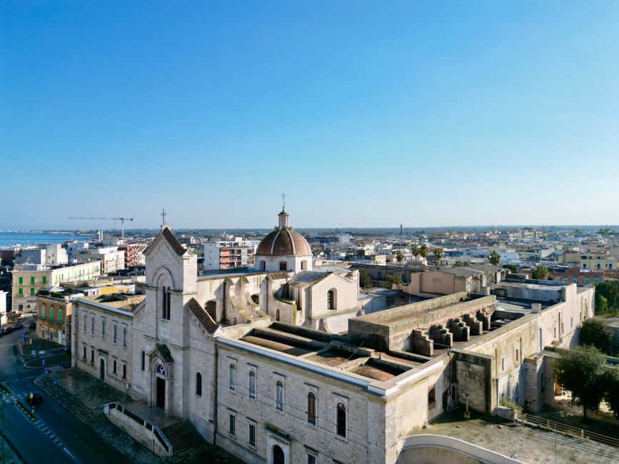 Aerial photograph of a historic church with a dome in Giovinazzo, Apulia, showcasing the city's architecture and skyline.