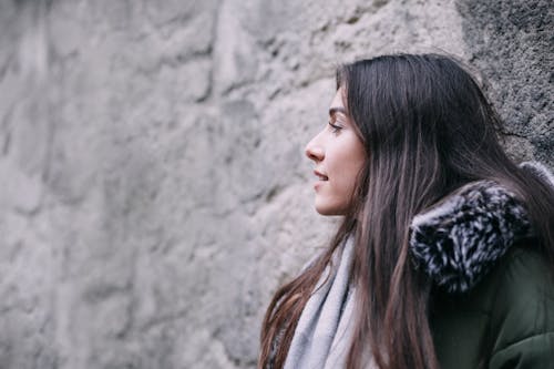 Woman Wearing Gray Winter Coat Leaning on Wall