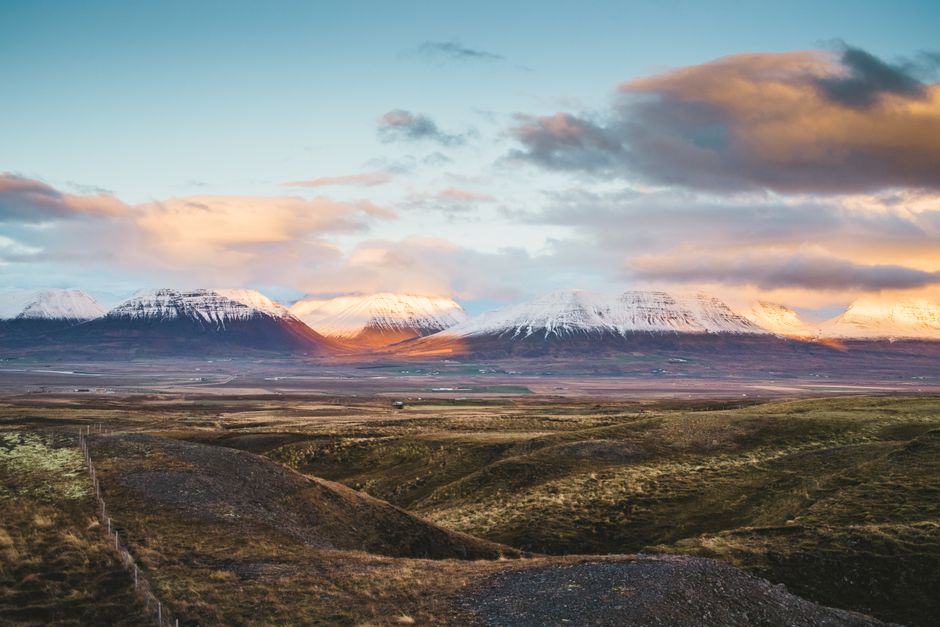 Breathtaking view of Icelandic mountains with snow caps under a vibrant sunrise sky.