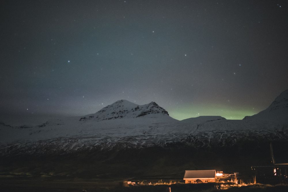 Aurora boreală verde deasupra munților înzăpeziți din Islanda