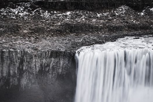 Breathtaking view of a waterfall cascading over rocky cliffs in Iceland, during winter.