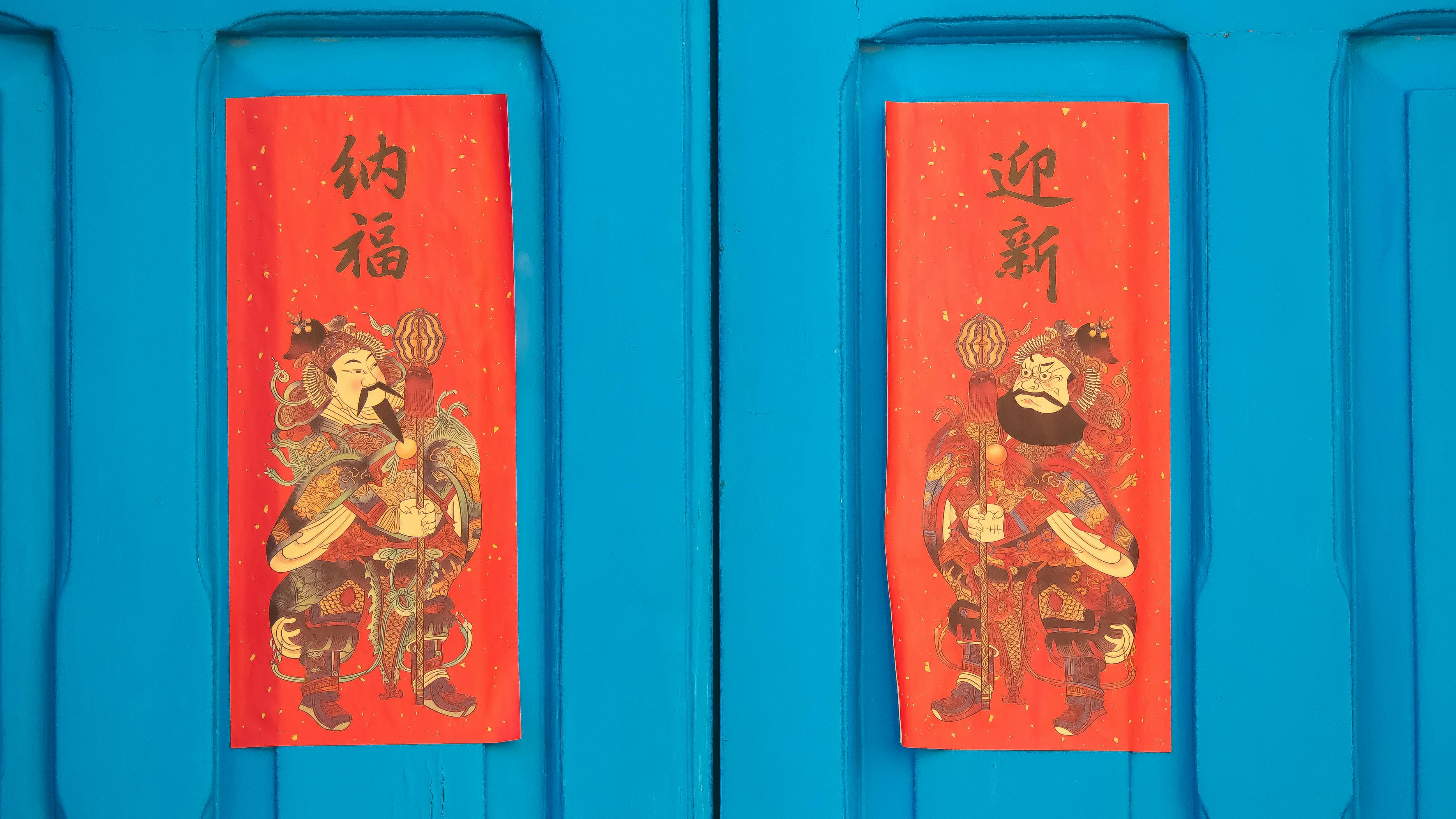 Bright red Chinese New Year decorations on a blue door symbolize good fortune and prosperity.