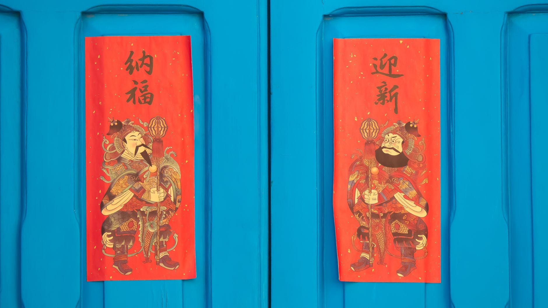 Bright red Chinese New Year decorations on a blue door symbolize good fortune and prosperity.
