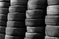 Black and white image of stacked vehicle tires showcasing various tread patterns.