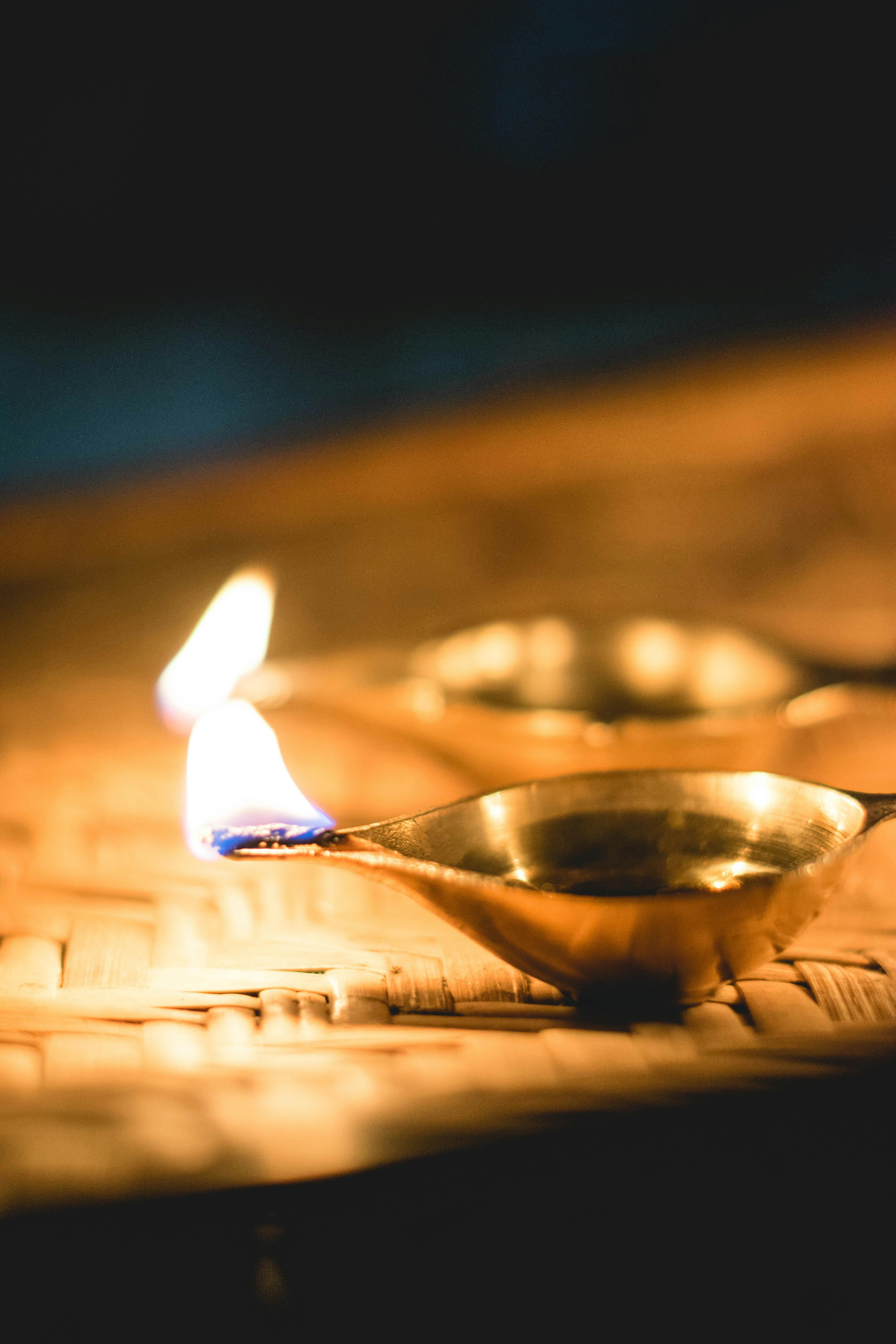 Close-up of lit oil lamps on a bamboo mat, creating a serene and warm ambiance.