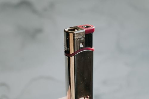 Free A metallic cigarette lighter with red accents, perfect for lifestyle concepts. Stock Photo