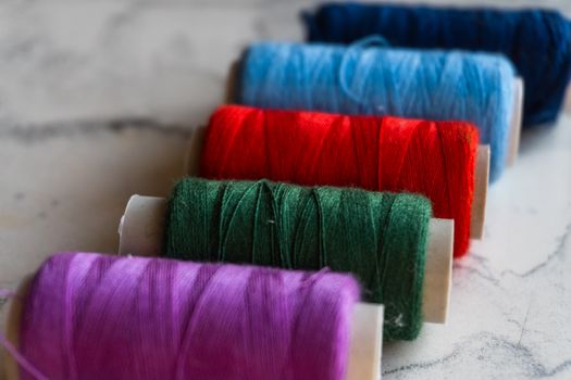 Vibrant spools of thread in multiple colors neatly arranged on a marble surface.