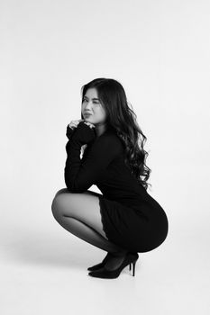 Black and white portrait of a woman squatting in a stylish pose, showing elegance and grace.
