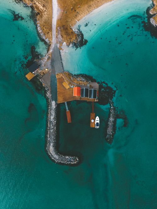 Free A stunning aerial photo of a coastal dock surrounded by turquoise waters in Troms, Norway. Stock Photo