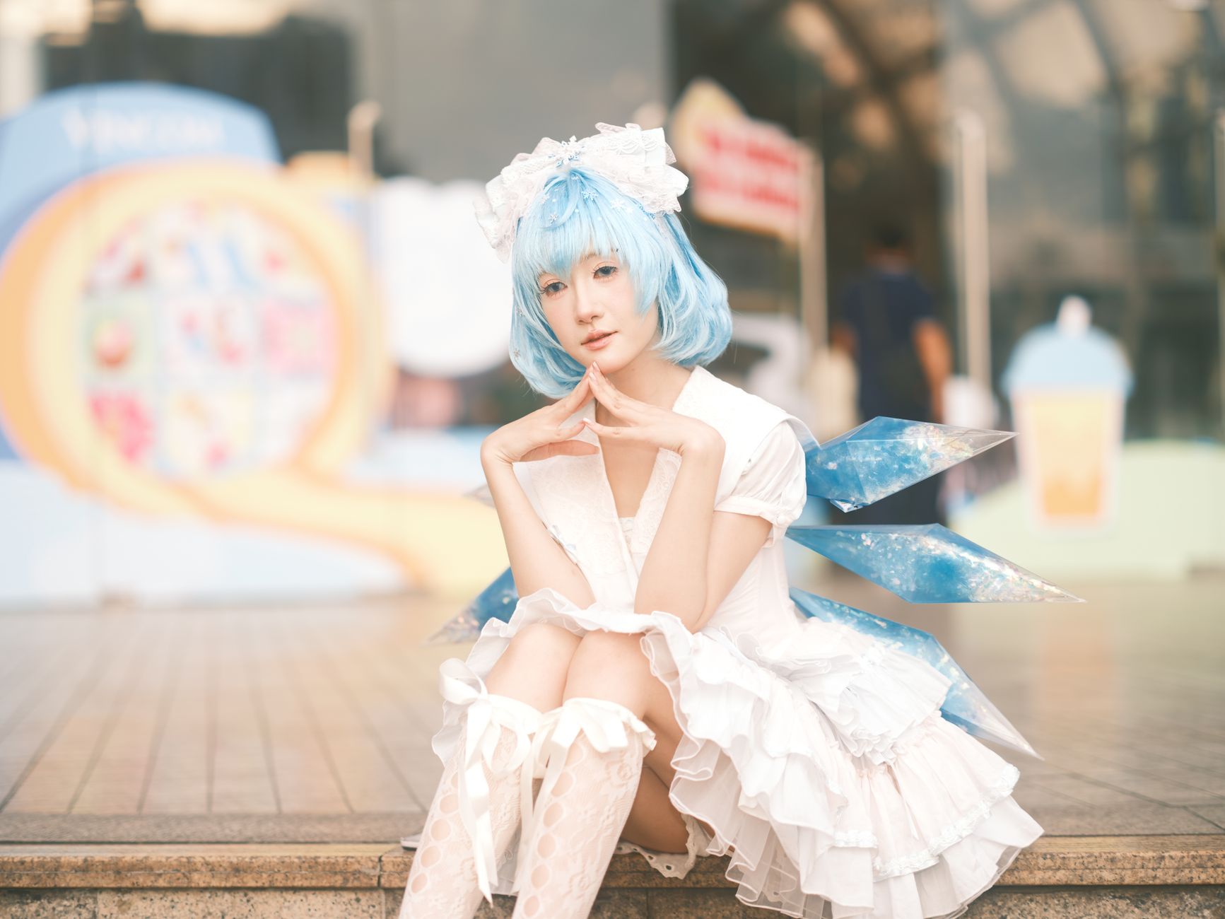 Cosplay enthusiast dressed as a blue-haired character sits outdoors in Vietnam.