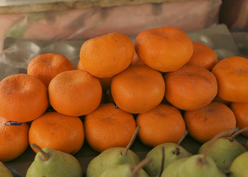 Free Fresh oranges and pears displayed at a market stall, showcasing vibrant colors and natural textures. Stock Photo