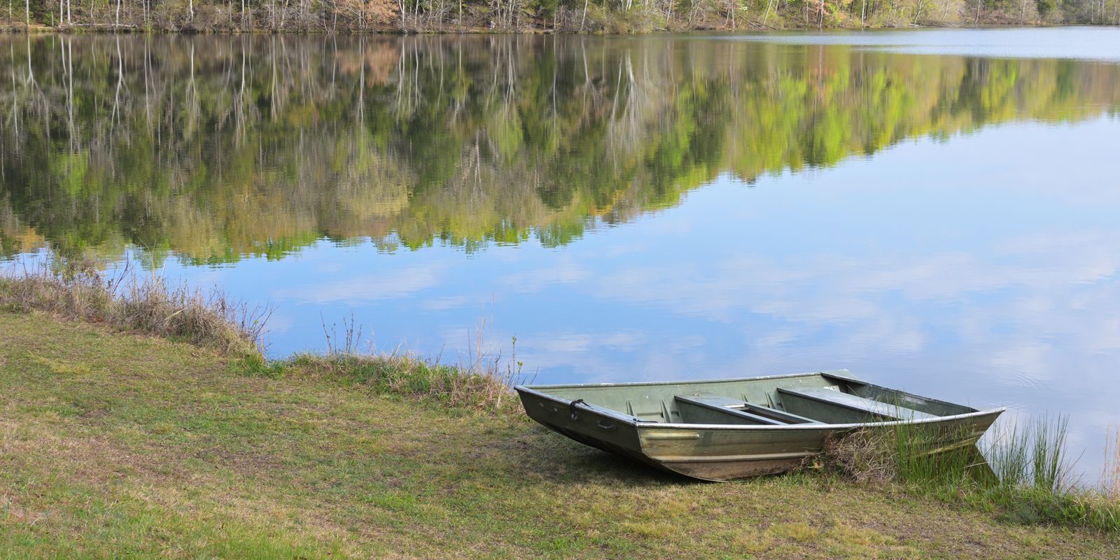 A peaceful morning at a lake with a boat reflecting in calm water