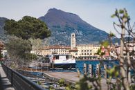 Charming lakeside town of Riva del Garda with picturesque mountains and a boat docked at the pier.