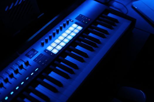 Close-up of an electronic keyboard illuminated by vibrant blue LED lighting, creating a moody atmosphere.